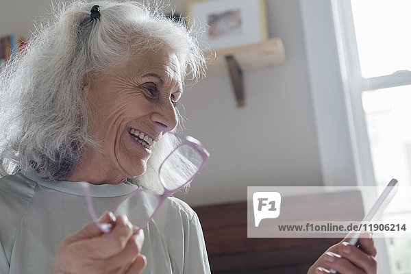 Ältere Frau  die eine SMS auf einem Mobiltelefon schreibt