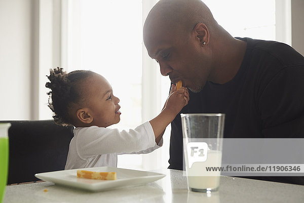 Black daughter feeding food to father