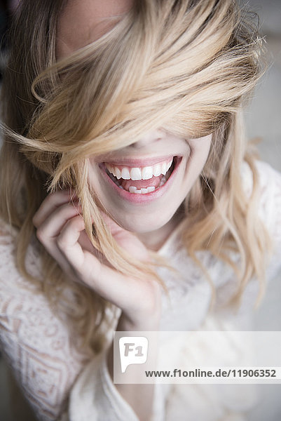 Laughing Caucasian woman covering eyes with hair