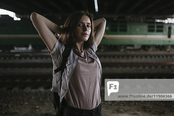 Caucasian woman stretching arms near train tracks at night