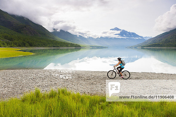 Mixed Race woman riding bicycle near lake