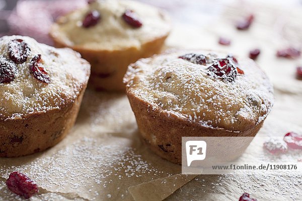 Frisch gebackene Cranberry-Muffins auf Pergamentpapier mit Zuckerguss