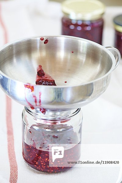 A jam jar with a metal funnel