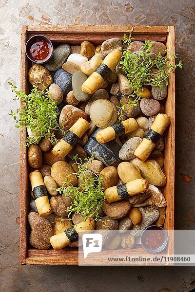 Spring rolls served on a wooden tray with stones (Asia)