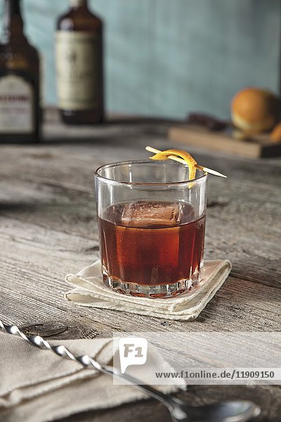 Whisky-Kirsch-Cocktail  garniert mit Orangenschale  aufgespießt mit Zahnstocher