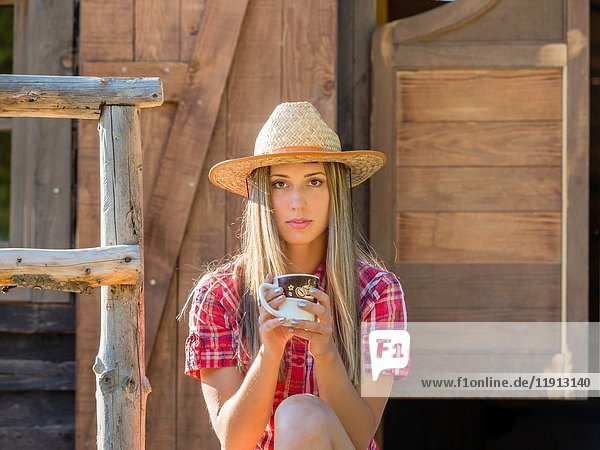 Country-girl with cup of coffee in hand facing camera