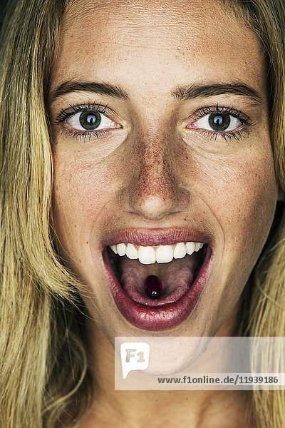 Junge Frau mit Gelkapsel auf der Zunge  Portrait