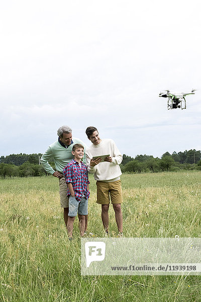 Multi-generation family playing with drone in field