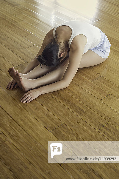 Woman stretching legs on floor
