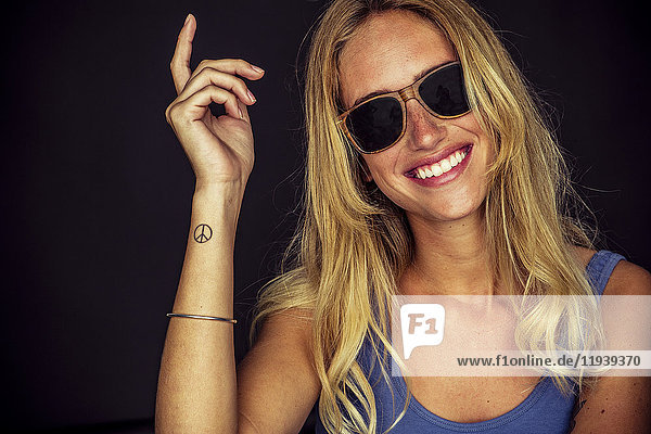 Young woman wearing sunglasses  smiling cheerfully  portrait