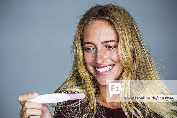 Junge Frau lächelt Schwangerschaftstest Ergebnisse