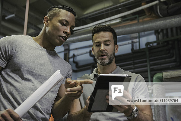 Men working in industrial setting using digital tablet