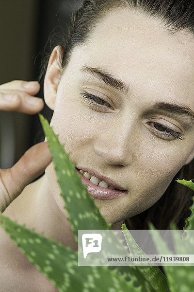 Junge Frau berührt Aloe Vera Pflanze