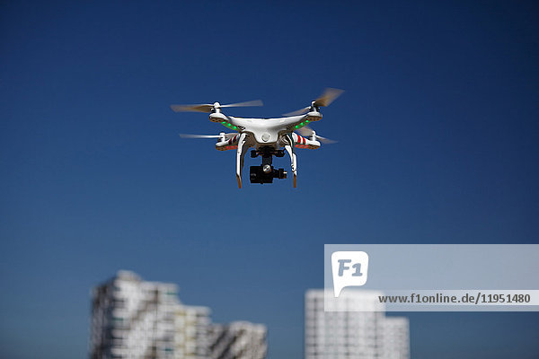 Drohne fliegt am blauen Himmel in der Nähe von Wohnblocks