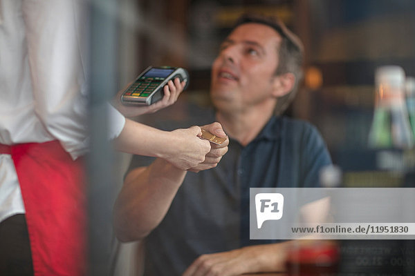 Kunde gibt Kreditkarte an Kellnerin zur Zahlung am Kartenautomaten ab
