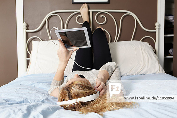 Frau benutzt digitales Tablett am Bett