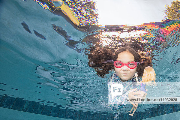 Underwater portrait of girl swimming holding doll