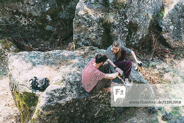 Hochwinkelaufnahme von zwei Boulderfreunden  die auf einem Felsblock sitzen  Lombardei  Italien