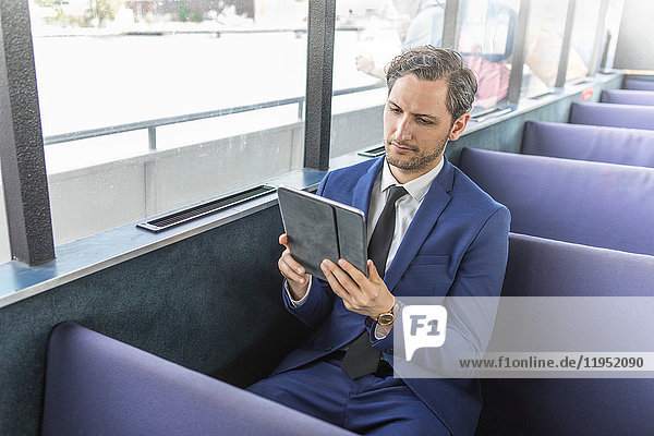 Junger Geschäftsmann betrachtet digitales Tablet auf Passagierfähre
