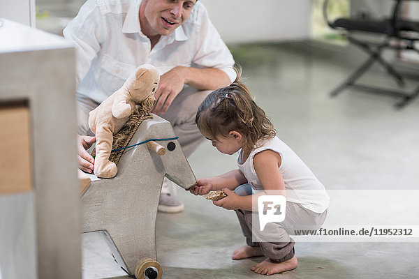 Father and baby girl looking at rocking horse