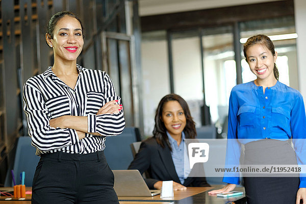 Porträt von drei Geschäftsfrauen im Großraumbüro  lächelnd