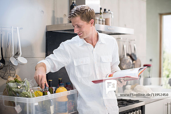 Man with recipe book  making preparations in kitchen