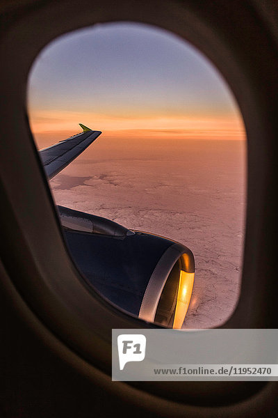 Sonnenuntergang Wolkenlandschaft und Flugzeugflügel durch Flugzeugfenster