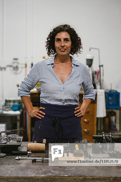 Portrait of mid adult female jeweller in jewellery workshop