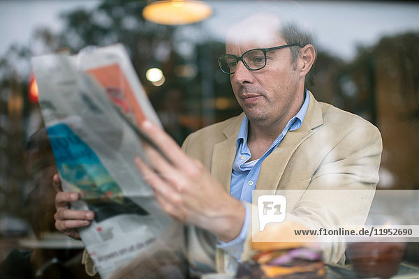 Mann im Café beim Zeitungslesen