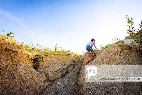 Teenagerin steht stehend und klettert steilen Steinbruch hinauf