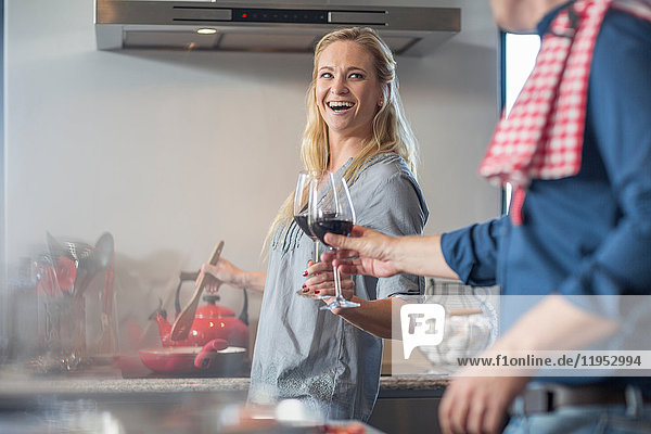 Man and woman in kitchen  preparing food  holding glass of wine  making a toast