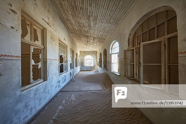 Blick auf einen Korridor in einem heruntergekommenen Gebäude voller Sand.