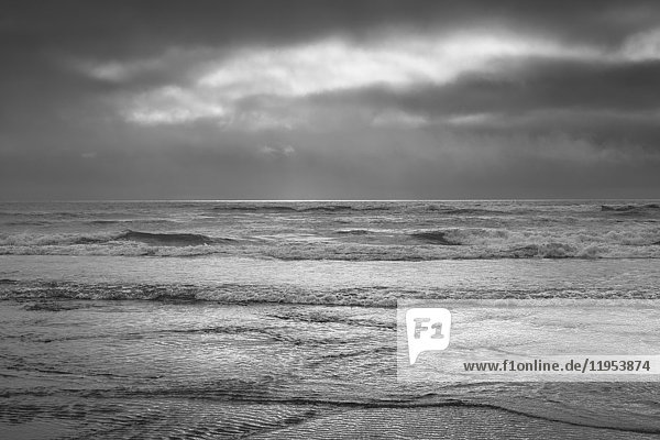 Blick vom Strand aufs Meer an einem bedeckten Tag und in der einsetzenden Dämmerung.