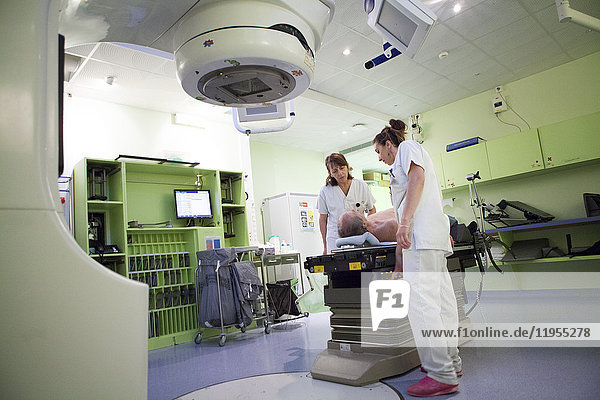 Reportage in der Strahlentherapieabteilung eines Krankenhauses in Savoie  Frankreich. Zwei Techniker bereiten einen Patienten für eine Strahlentherapie zur Behandlung eines Adenokarzinoms der Hals- und Rückenwirbelsäule vor.