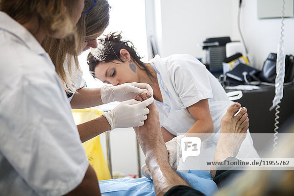 Reportage über die Fußsprechstunde für Diabetiker in einem Krankenhaus in Savoyen  Frankreich. Diese Beratungen werden von einem spezialisierten Team durchgeführt und sind der Behandlung und Nachsorge von Fußverletzungen bei Diabetikern gewidmet. Die Krankenschwester und die Fußpflegerin untersuchen den Fuß eines Patienten.
