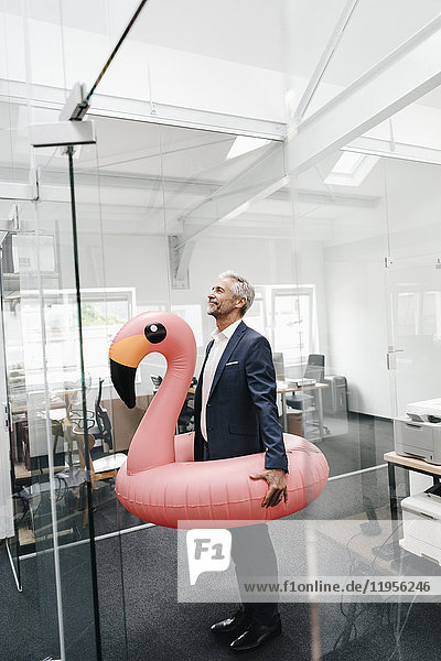 Businessman in office with inflatable flamingo