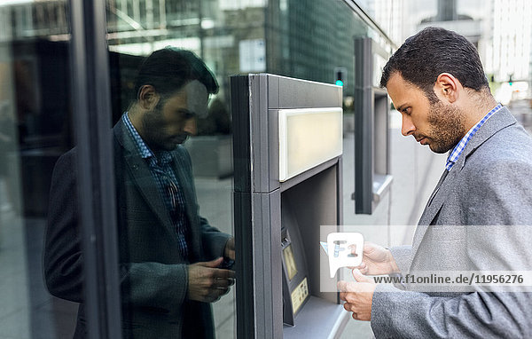 Businessman taking money at an ATM in the city