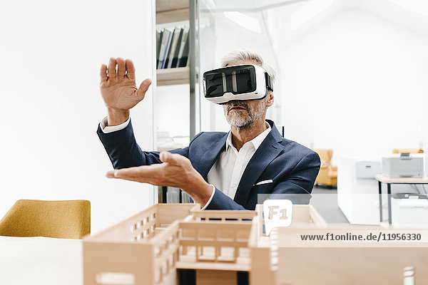 Ausgereifter Geschäftsmann mit Architekturmodell im Büro mit VR-Brille