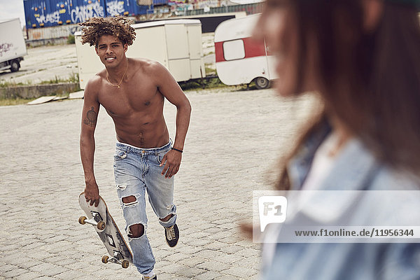 Young man with skateboard running to his girlfriend