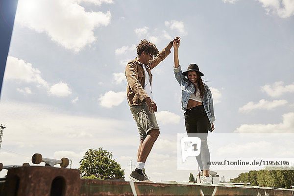 Young couple standing on wall  raising arms