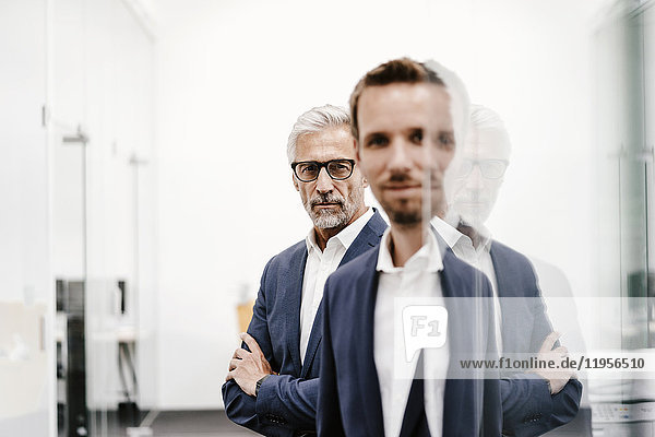Portrait of two businessmen at glass pane