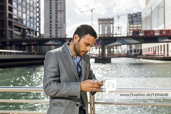 Businessman sending messages with his smartphone in the city