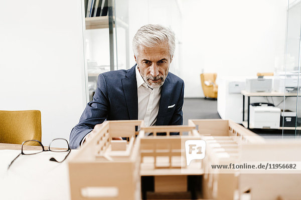 Mature businessman examining architectural model in office