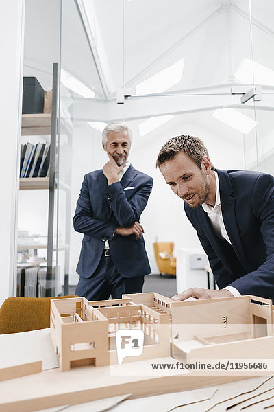 Two businessmen examining architectural model in office