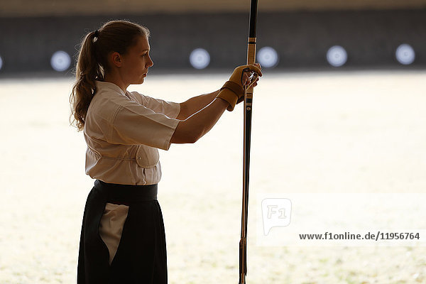 Caucasian woman practicing traditional Kyudo Japanese archery