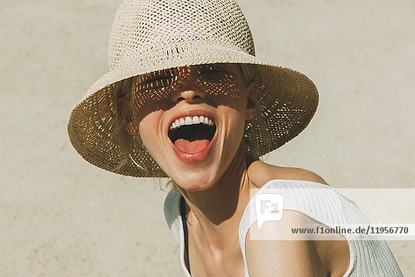 Porträt einer lachenden blonden Frau mit Sommerhut