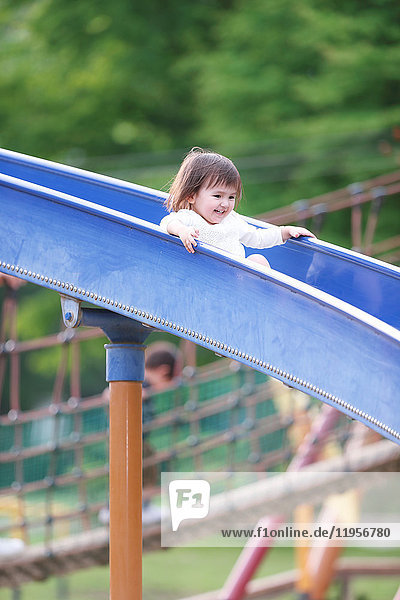 Mixed-race young girl playing on slide at the park