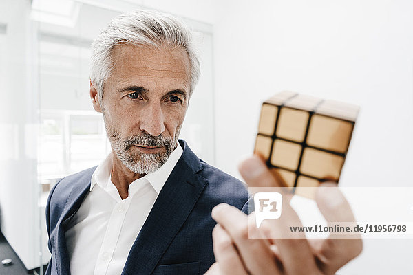 Mature businessman in office examining Rubik's Cube