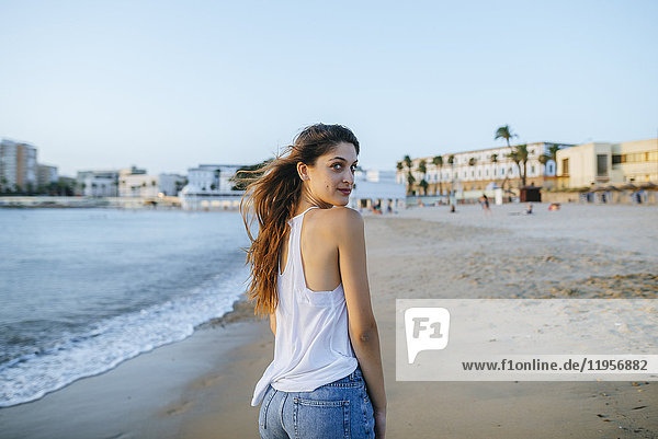 Porträt einer jungen Frau beim Spaziergang am Strand