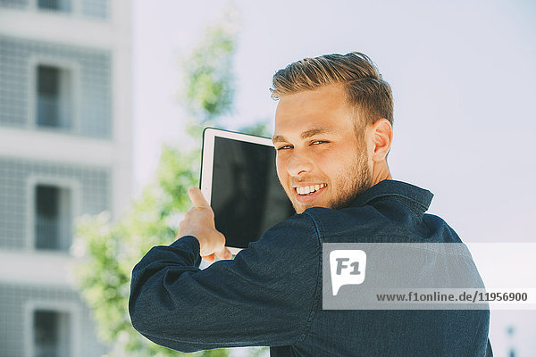 Portrait of smiling young man taking picture with tablet